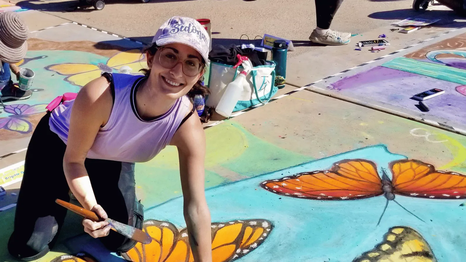 Brigitte De Marco creating a monarch butterfly chalk piece at a community festival