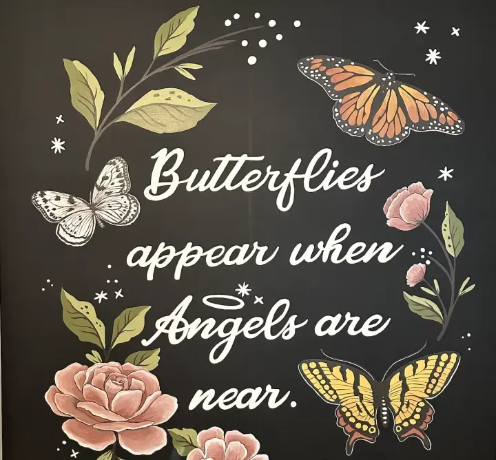 Hand-lettered wall reading Butterflies appear when Angels are near, with painted butterflies and roses