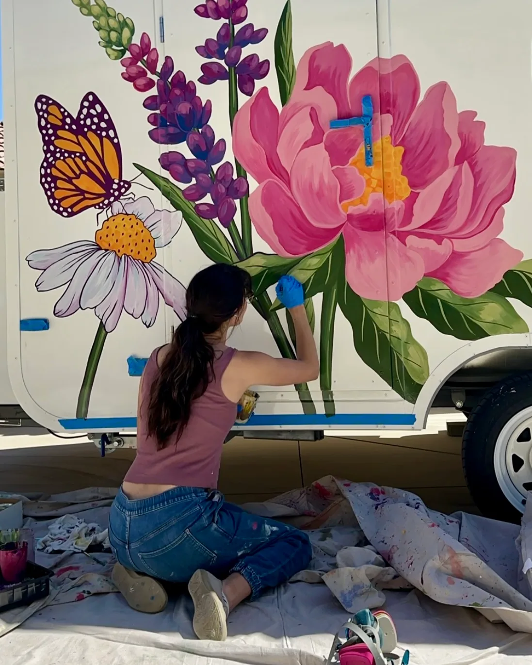 Brigitte De Marco painting giant peonies and a monarch butterfly on the Keep it Non-Toxic trailer